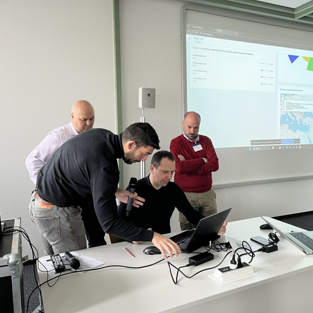 4 FALCON members behind a laptop discussing a FALCON tool